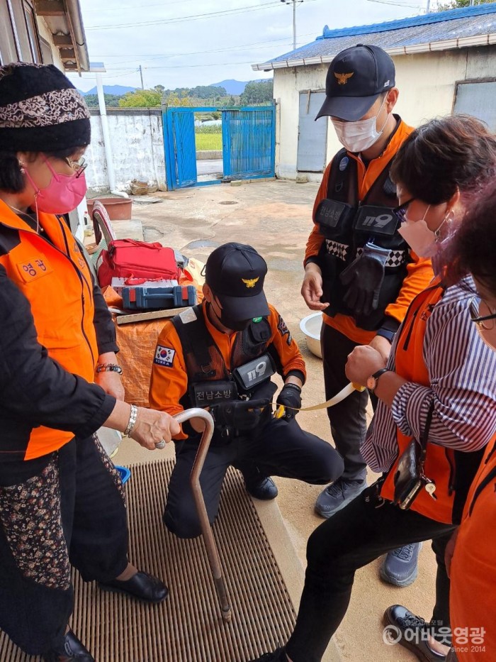 영광소방서와 영광읍 의용소방대원과 취약계층 가구를 방문해 어르신 지팡이에 야광테이프를 붙이고있다..jpg