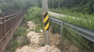 영광군 불갑저수지 ‘물멍쉼터’로 이어지는 데크길 인근. 가드레일 아래 토사가 심하게 쓸려 내려갔고, 전신주는 한쪽으로 기울어진 채 방치돼 있어 안전사고 우려가 제기된다..jpg